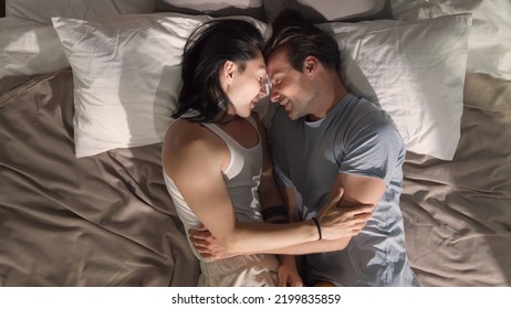 Top View Of Mixed Race Gay Men Sharing Love And Support Cuddling. Multiethnic Homosexual Male Couple Lie On Bed, Looking Each Other Eyes. Intimate Moment.