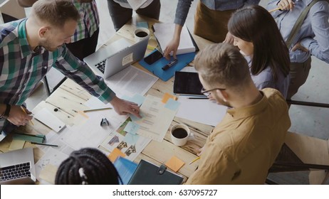 Top View Of Mixed Race Group Of People Standing Near The Table. Young Business Team Working On Start-up Project Together