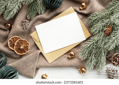 Top view mockup blank paper and envelope . Flat lay of white wooden background,  Christmas decorations and brown sweater - Powered by Shutterstock