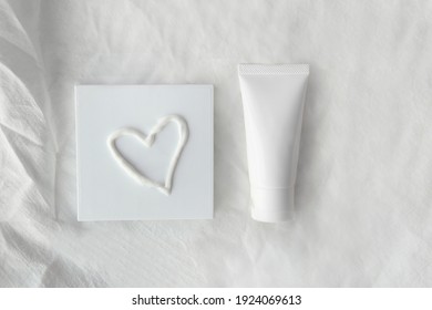 Top View Mockup Blank White Label Packaging Organic Facial Gentle Skincare White Tube Bottle Product Next To Squeeze Lotion Heart Shape With Minimal Soft Crumpled White Fabric Cloth Clean Background