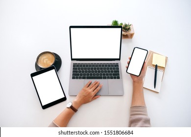 Top View Mockup Image Of Hands Holding A Blank White Screen Mobile Phone With Laptop Computer And Tablet Pc On The Table In Office