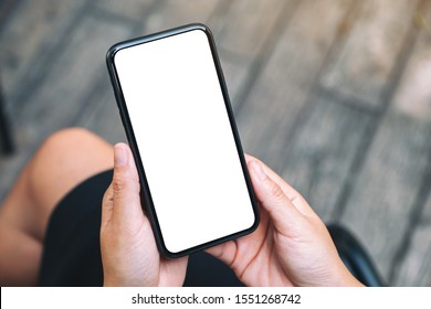 Top View Mockup Image Of A Woman Holding A Black Mobile Phone With Blank White Desktop Screen 