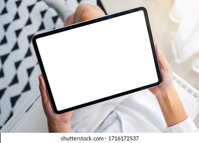 Top view mockup image of a woman holding black tablet pc with blank white desktop screen while sitting in bedroom with feeling relaxed in the morning - Powered by Shutterstock