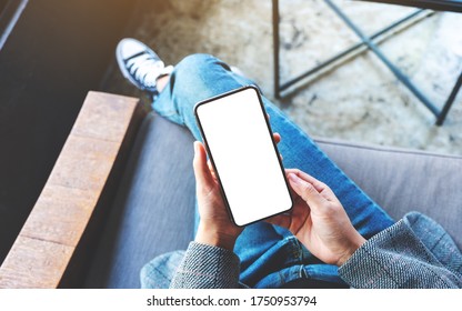 Top View Mockup Image Of A Woman Holding A Black Mobile Phone With Blank White Desktop Screen