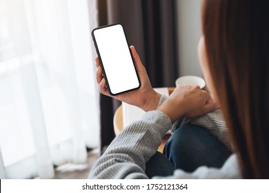 Top view mockup image of a woman holding mobile phone with blank desktop screen while sitting in bed room at home - Shutterstock ID 1752121364