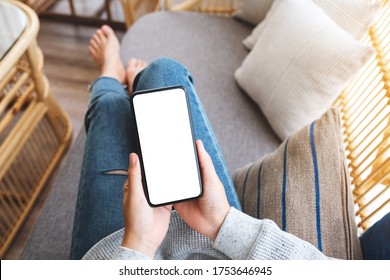 Top View Mockup Image Of A Woman Holding Mobile Phone With Blank Desktop White Screen While Lying On A Sofa At Home