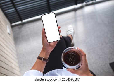 Top view mockup image of a woman holding mobile phone with blank screen and coffee cup