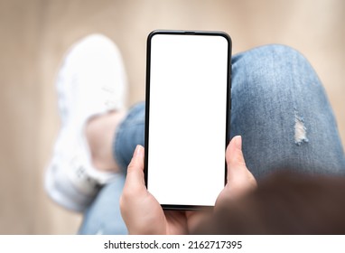 Top view mockup image of woman holding mobile phone with blank white screen. mockup image of woman using cellphone with while sitting on sofa - Shutterstock ID 2162717395