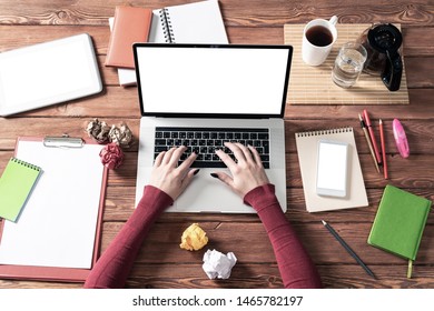 Top view modern office workspace with woman hands. Flat lay wooden desk with laptop keyboard, cup of coffee and crumpling paper balls. Business woman hands working at computer with blank screen. - Powered by Shutterstock