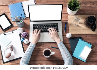 Top view modern office workspace with woman hands. Flat lay wooden desk with laptop keyboard, cup of coffee and crumpling paper balls. Business woman hands working at computer with blank screen. - Powered by Shutterstock