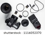 top view of modern photo camera, lenses and equipment over white table background