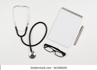 Top View Of Modern, Sterile Doctors Office Desk. Medical Accessories On A White Background With Copy Space Around Products. Photo Taken From Above.