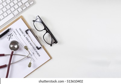 Top View Of Modern, Sterile Doctors Office Desk. Medical Accessories On A White Background With Copy Space Around Products.Stethoscope, Clip Board, Glasses And Other Things