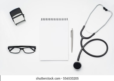 Top View Of Modern, Sterile Doctors Office Desk. Medical Accessories On A White Table Background With Copy Space Around Products. Photo Taken From Above.