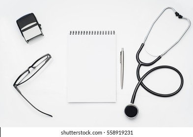 Top View Of Modern, Sterile Doctors Office Desk. Medical Accessories On A White Table Background With Copy Space Around Products. Photo Taken From Above.