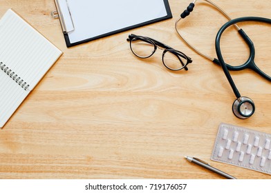 Top View Of Modern, Sterile Doctors Office Desk. Medical Accessories On A Wooden Table Background With Copy Space Around Products. Photo Taken From Above.