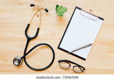 Top View Of Modern, Sterile Doctors Office Desk. Medical Accessories On A Wooden Table Background With Copy Space Around Products. Photo Taken From Above.