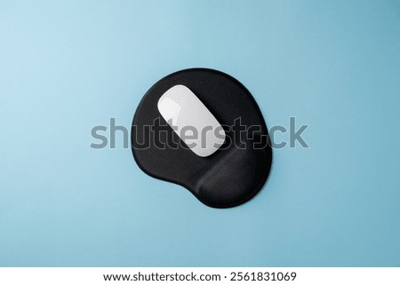 Top view of modern white mouse on black mousepad on blue table