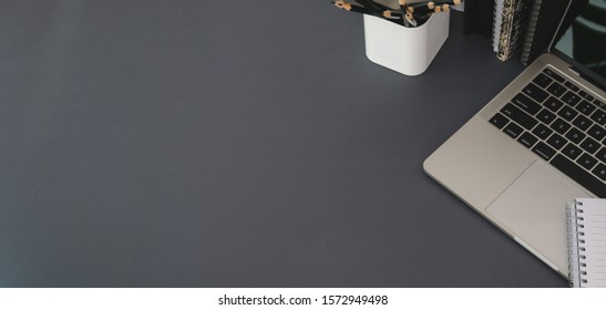 Top View Of Modern Workplace With Laptop Computer And Office Supplies On Dark Grey Table Background