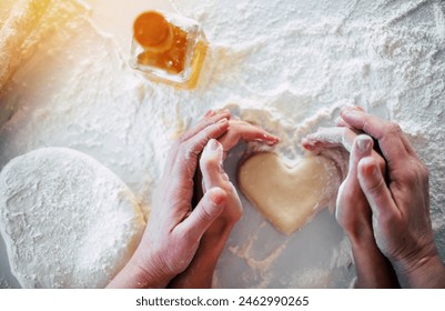 Top view of mom and daughter hands making dough heart for cookies at home domestic kitchen. Close up image of females hands making sign in the shape of heart during baking process - Powered by Shutterstock