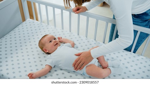 Top view. Mom playing to adorable newborn baby on bed smiling and happiness at home. Happy baby boy smile and laugh loudly.