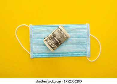 Top View Of Money Roll And Medical Mask On Yellow Background