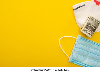 Top View Of Money Roll, Safety And Medical Masks On Yellow Background