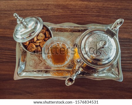 Top view of Moroccan tea pot with a cup of tea with some moroccan cakes on table - Moroccan Tea