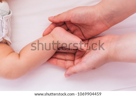 Top view of mother hands holding tiny baby feet