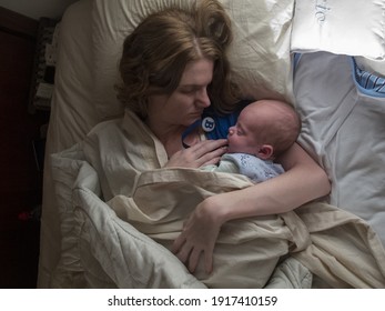 Eine Draufsicht einer Mutter, die ihr neugeborenes schlafendes Baby auf einem Bett umarmt