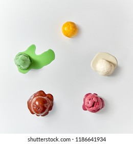 Top View Of Multi-colored Balls Of Melted Ice Cream - White, Brown , Green , Yellow , Red On A White Background. Summer Fresh Food Concept.