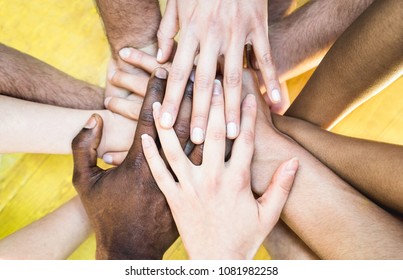 Top view of multicolored stacking hands - International friendship concept with multiethnic people representing peace and unity against racism - Multi racial love and integration between diversity