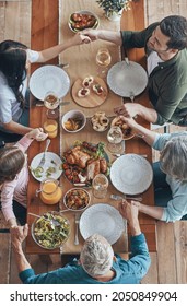 Top View Of Multi-generation Family Holding Hands And Praying While Having Dinner Together