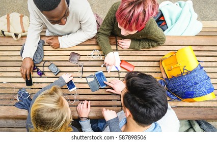 Top view of multiracial friends using mobile smart phone - Addiction concept with young people on new tech devices - Multicultural students having fun on social media networking - Warm vivid filter