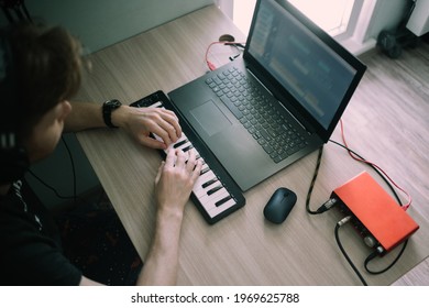 Top view of music producer or arranger using laptop, midi keyboard, and other audio equipmen to create music at home studio