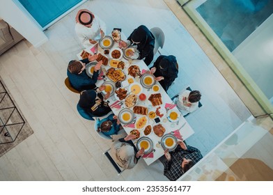 Top view of Muslim family having Iftar dinner drinking water to break feast. Eating traditional food during Ramadan feasting month at home. The Islamic Halal Eating and Drinking in modern home 