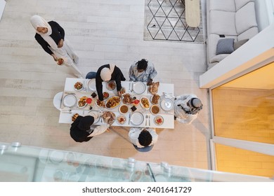 Top view of a Muslim family joyously comes together around a table, eagerly awaiting the communal iftar, engaging in the preparation of a shared meal, and uniting in anticipation of a collective - Powered by Shutterstock