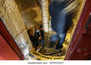 Top view of narrow spiral stone staircase with blurred people ascending