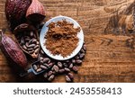 Top view of Natural cocoa powder with brown cocoa beans and dry cacao pod  on a vintage wooden table.