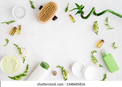 Top View Of Natural Skincare And Spa Cosmetic Products On White Marble Table, Flat Lay. Frame Of Cream, Oil, Sea Bath Salt, Massage Brush, Bamboo And Flower Buds. Beauty Flatlay Concept