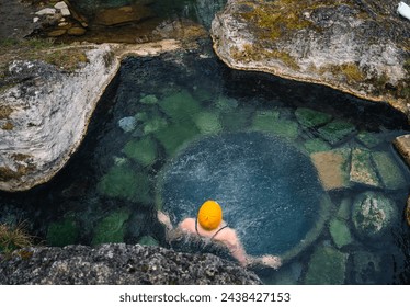 Top view of a natural thermal pool. Woman in a yellow cap relaxing in a thermal bath in Slovakia. In the Low Tatras National Park. Thermal baths almost like in Iceland - Powered by Shutterstock