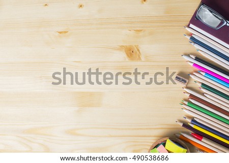Top view of natural wooden desktop with colorful supplies. Mock up