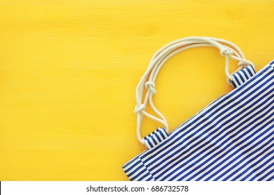 Top View Of Nautical Summer/beach Bag On Yellow Wooden Background.