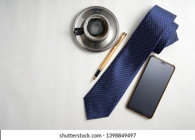 Top View Of Neck Tie,hand Phone,pen And Cup Of Coffee On The White Background