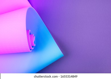 Top View Of Neon Colored Blue Pink Yoga Mat On Violet Background. Yoga Pilates Sport Concept. Flat Lay. 