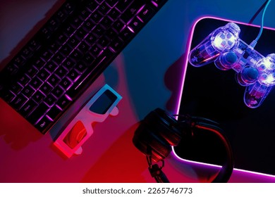 Top view of neon gaming keyboard setup controller pro gaming illuminated desk along with headset, keyboard, computer neon lights. - Powered by Shutterstock - Get 15% off with code: PIKWIZARD15