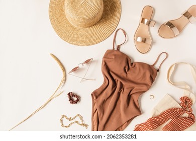 Top view of neutral colours women's clothes and accessories for summer vacation beach chill on white background. Luxury aesthetic sexy fashion female lifestyle cloth. Flat lay of dusty pink swimsuit