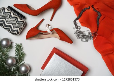 Top View To New Year And Christmas Party Outfit Composition Red Shoes Accessories Jewelry Clutch Fir Tree With Balls White Background. Party Date Night Conception. Flat Lay, Copy Space