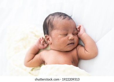 Top view of Newborn baby sleeping with blanket on white bed. Infant lying on white bed. African American newborn baby. Afro infant