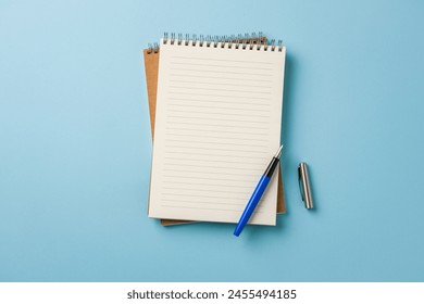 Top view of notebook and fountain pen on blue background